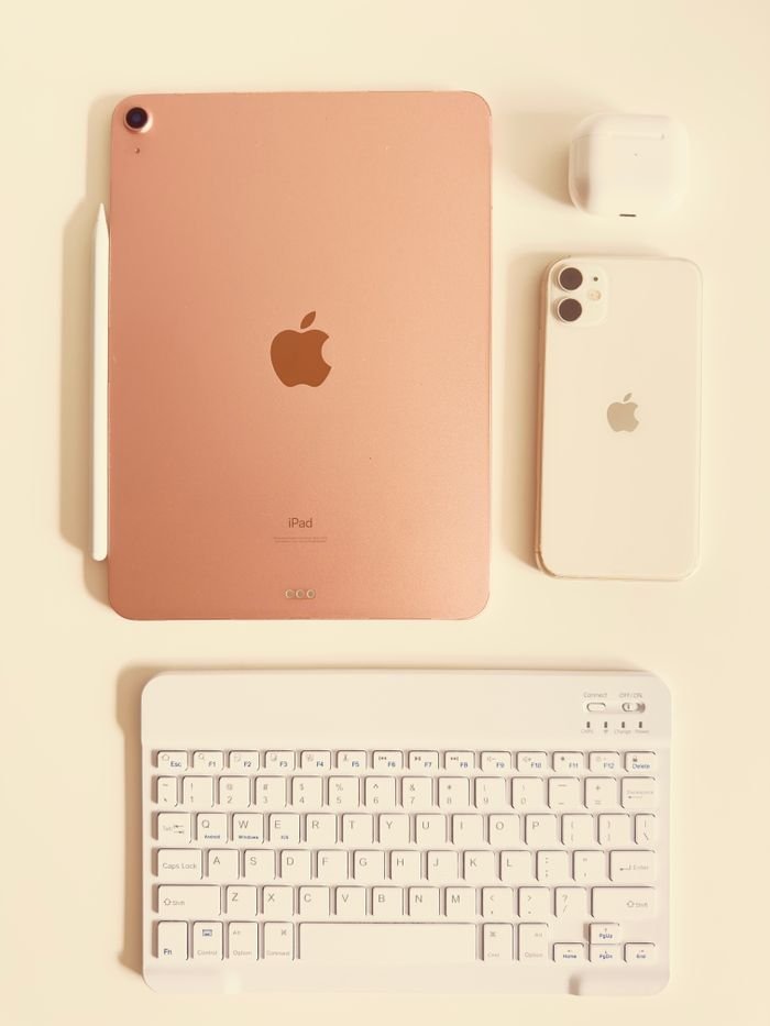 Minimalist flat lay of tech gadgets including tablet, phone, and keyboard with elegant design