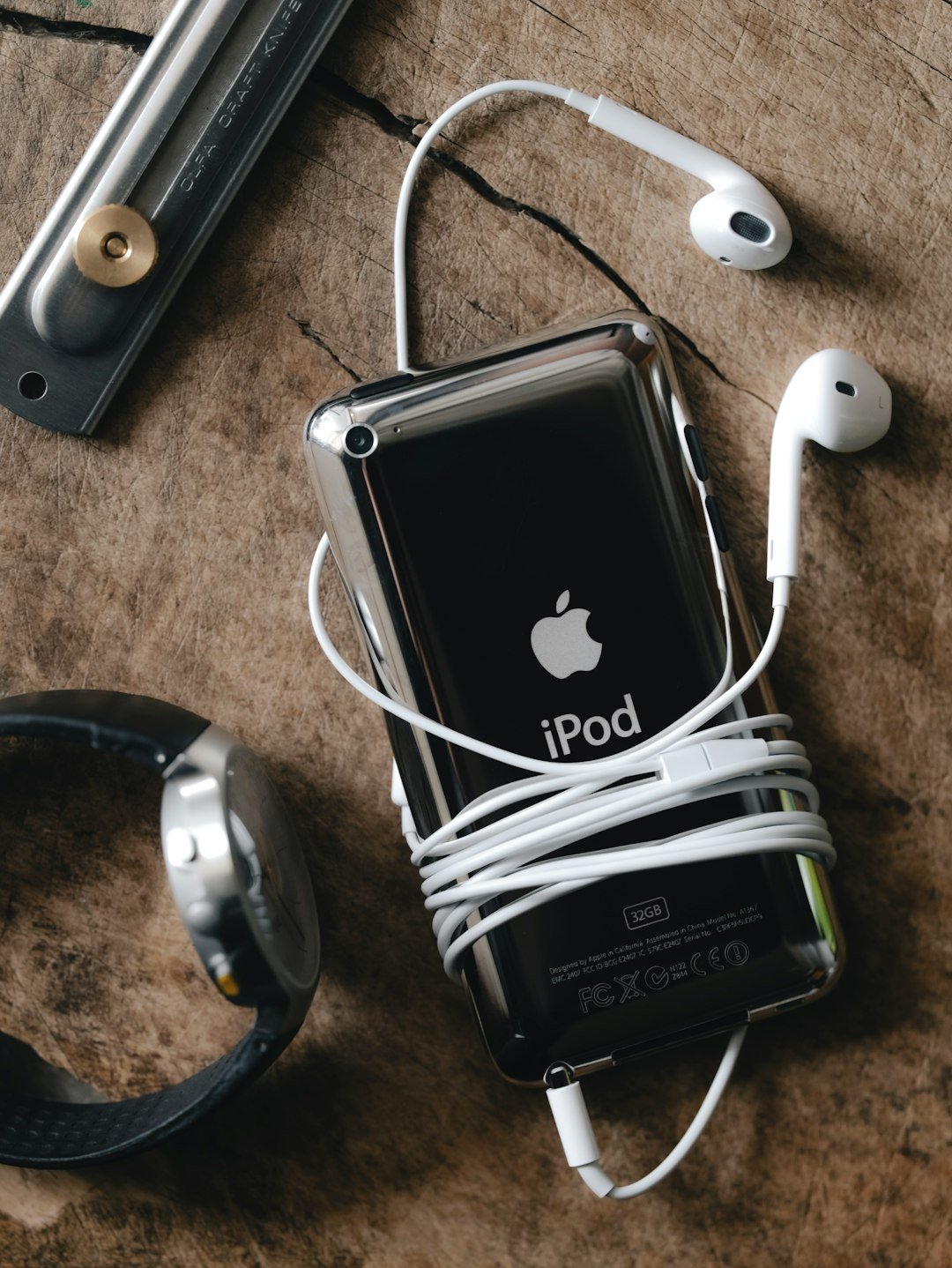 ipod-with-earphones-and-wristwatch-on-wooden-surface-er9sh2klbmk